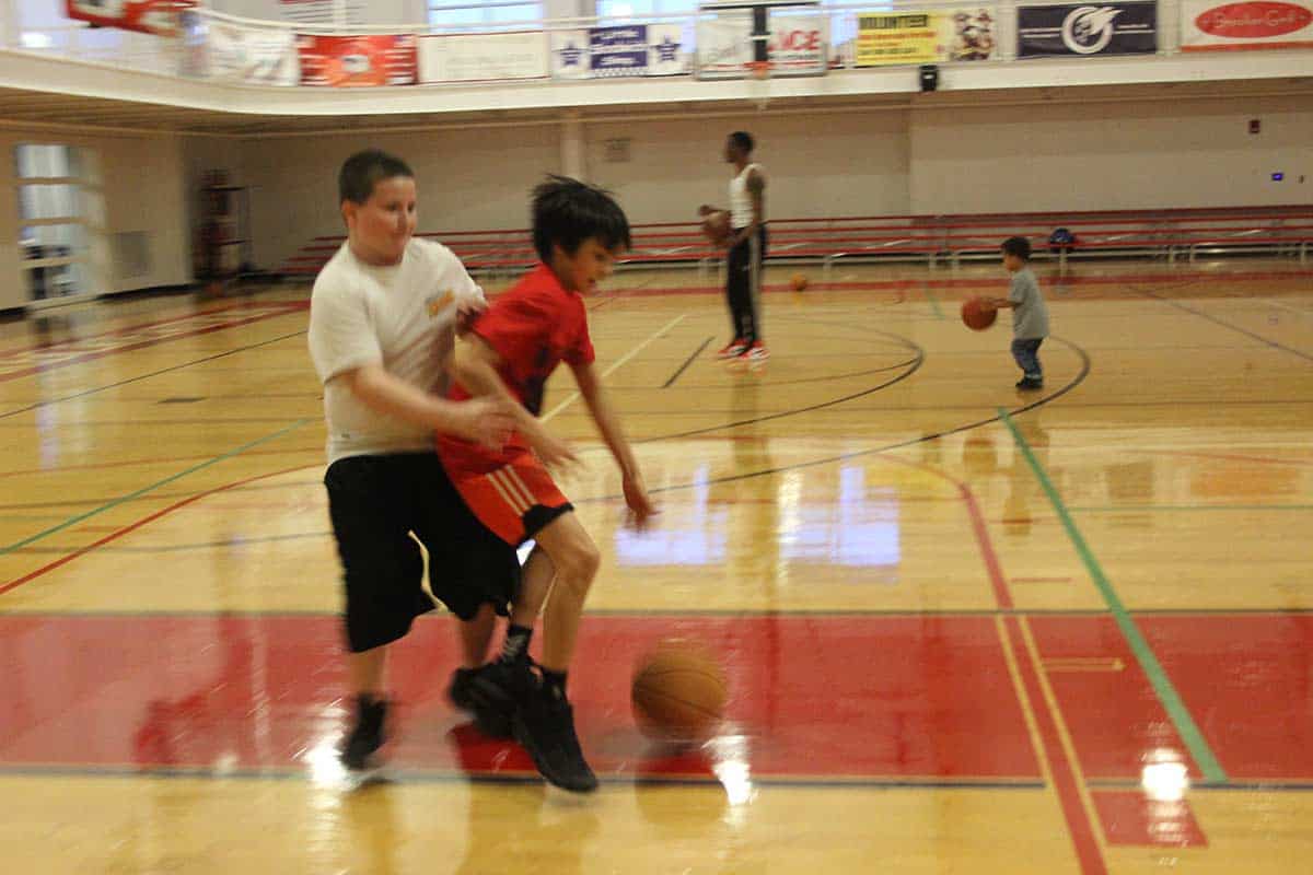 two kids playing basketball inside the gym