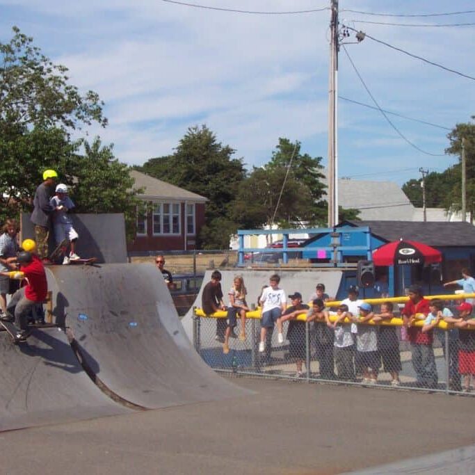 kids on skateboards atop a large half pipe ramp are ready to skate